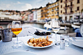 Fried Seafood and aperitif on set table with harbor view (Italy)