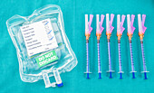 Syringes next to medical fluid bag, conceptual image
