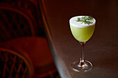 A green cocktail garnished with dill