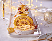 Festive sponge cake roll with jam and nut filling, candied lemon and spun sugar