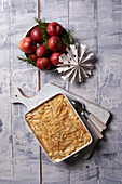 Potato and anchovy casserole with Christmas decoration and red apples