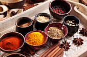 Various spices in small bowls on a wooden tray