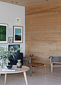 Coffeetable und Sitzmöbel in hellem Raum mit Bildergalerei und Durchgang mit Holzverkleidung