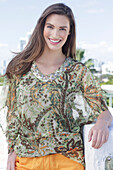 A young woman wearing a colorful, airy summer blouse