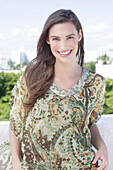 A young woman wearing a colorful, airy summer blouse