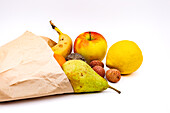 A sustainable paper bag with various fruits isolated as a studio shot against a white background