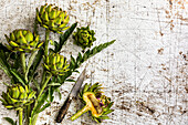 Artichokes with knife on wooden background
