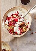 Crumbly oat bars with pomegranate and pumpkin seeds served with plain white yoghurt, raspberries