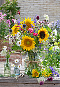 Bouquet of summer flowers with sunflowers, ornamental cranesbills, globe thistles, roses, and yarrow