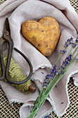 Herzförmige Kartoffel mit Garn, Gartenschere und Lavendelzweigen