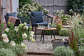Sitzplatz mit Tisch, Stühlen und Miniteich auf sommerlicher Kies-Terrasse