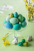 Blue and green colored Easter eggs in glass bowl