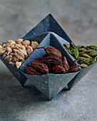 Cardamom pods (white, black and green) in origami paper bowls