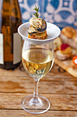 A glass of white wine and pincho of oysters