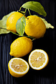 Frische Zitronen, ganz und halbiert mit Blättern