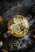 Spicy winter tea with lemon, cinnamon, and cardamom in glass teapot