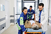 Paramedics and doctor wheeling patient