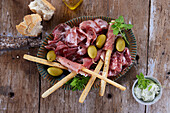 Antipasti platter with ham, salami, olives, and breadsticks