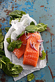Fresh salmon with spinach leaves on paper