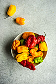 Bowl full of raw different colors chilli peppers on concrete background