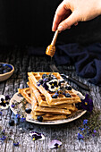 Waffles with blueberries, honey, icing sugar, pansies and forget-me-nots