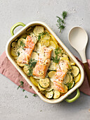 Potato and zucchini casserole topped with salmon