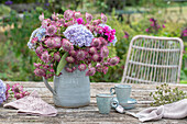 Blumenstrauß mit Sterndolde, Hortensien und Phlox in Krug auf Gartentisch