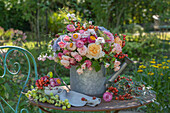 Bouquet of roses with sweet peas, hydrangeas, strawflowers, blackberry twigs, and rose hips in watering can