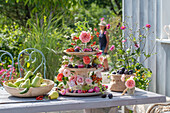 Etagere mit Rosenblüten, Strohblumen, Duftwicken, Hagebutten und Herbstfrüchten als Tischdekoration