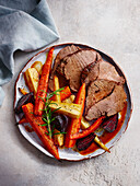 Sliced peppered roast beef with roasted root vegetables