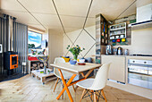 Heller, offener Wohnraum mit kleinem Essbereich und Küche, rautenförmige Decke mit LED-Leisten