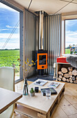 Pallet table and wood-burning stove in bright room with floor-to-ceiling windows