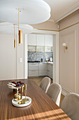 Dining area in elegant living room in pastel shades, view into the kitchen