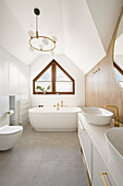 Vanity and freestanding bath under window in white bathroom
