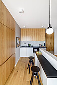 Single young man apartment, kitchen, gray colors combined with light walnut wood, light oak floor panels on the floor matching the color of the cabinet fronts, black male accents in furniture and decorations