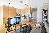 Offener Wohnraum in Grautönen in einer maskulinen Single-Wohnung, multifunktionale Küchentheke mit TV-Wand in der Vorderseite