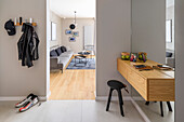 Hallway with wall mounted entryway in walnut, view into the living room in grey tones