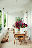 Wooden table with flower pots and a dog on floor on covered veranda