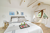 White bedroom in the attic with double bed and hanging hammock in a boho style