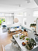 Kitchen island with marbled worktop and dining area with integrated bench in open-plan living area