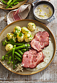 Smoked pork neck with horseradish sauce, beans and potatoes