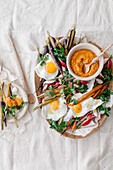 Fried eggs with colourful root vegetables and hummus