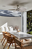 Covered terrace with table and chairs, bench in the background