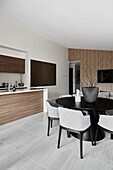 Offene Küche und Essbereich mit schwarzem Säulentisch und  grau gepolsterten Stühlen