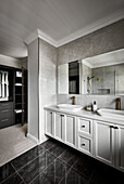 Opulent bathroom in dark tones with black marble tiles and Shaker-style double sink vanity