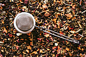 Teesieb aus Metall auf getrocknetem Tee aus Früchten und Blüten