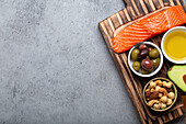 Food sources of healthy unsaturated fat and omega 3: fresh salmon fillet, avocado, olives and nuts