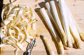 White asparagus, peeled, with peeler on wooden board outside