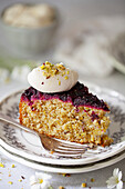Crumbled blackcurrant cake with whipped cream and chopped pistachios