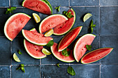 Watermelon slices with mint and lime on blue tiles